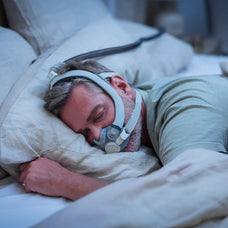 A man is sleeping on his stomach sideways with the F30i mask on
