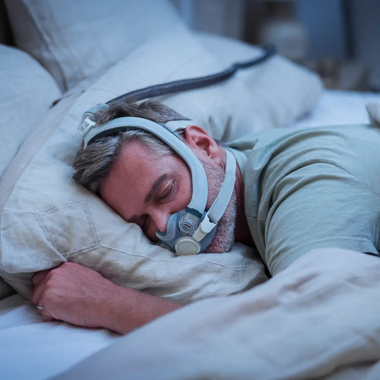 A man is sleeping on his stomach sideways with the F30i mask on