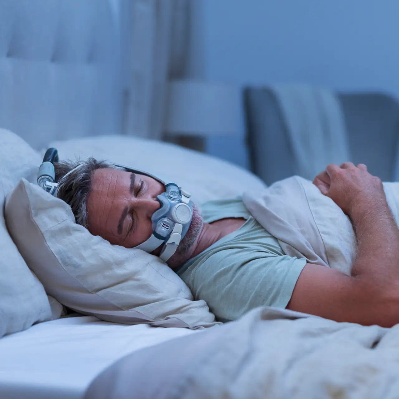 Man is sleeping on his back, with the F30i mask on, his head is on the side.