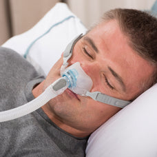 Man sleeping with CPAP therapy using Fisher and Paykel Brevida Nasal Pillow Mask